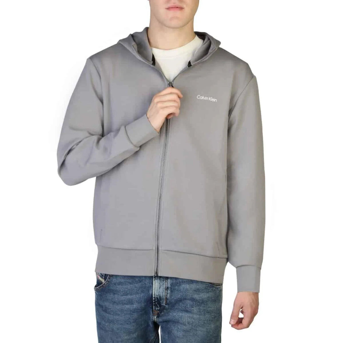 Man in a grey zip-up sweatshirt worn over a white t-shirt and jeans fashion image