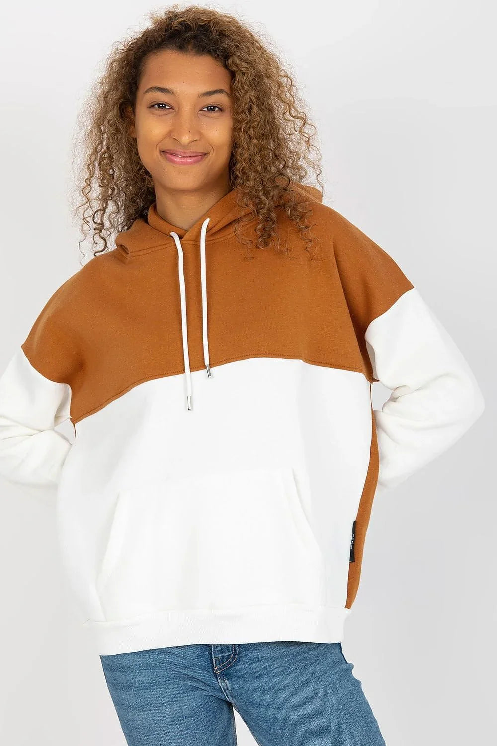 Woman in a caramel and white colour-block pullover hoodie with jeans fashion image