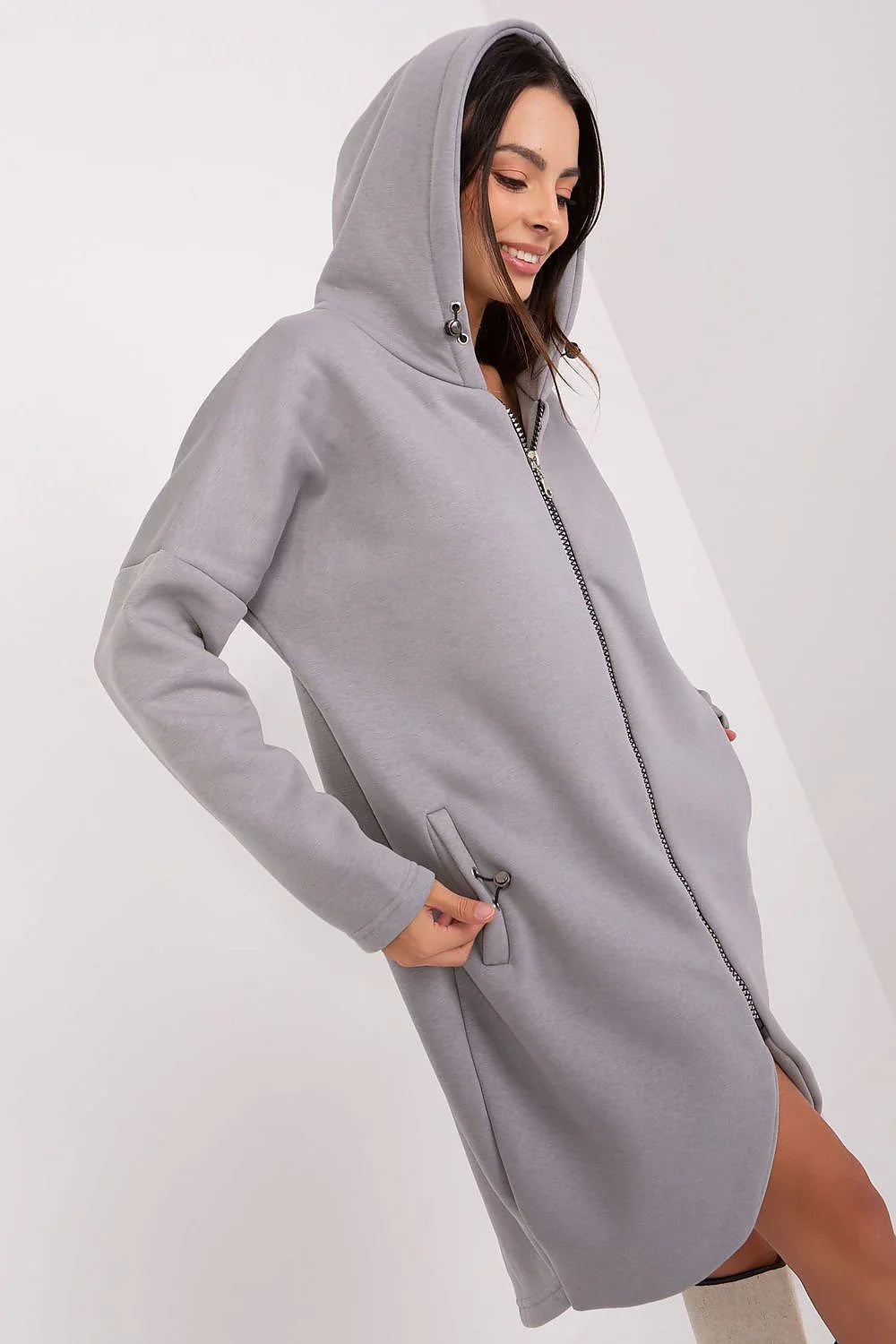 Woman in a long grey zip-up hooded sweatshirt with side pockets fashion image