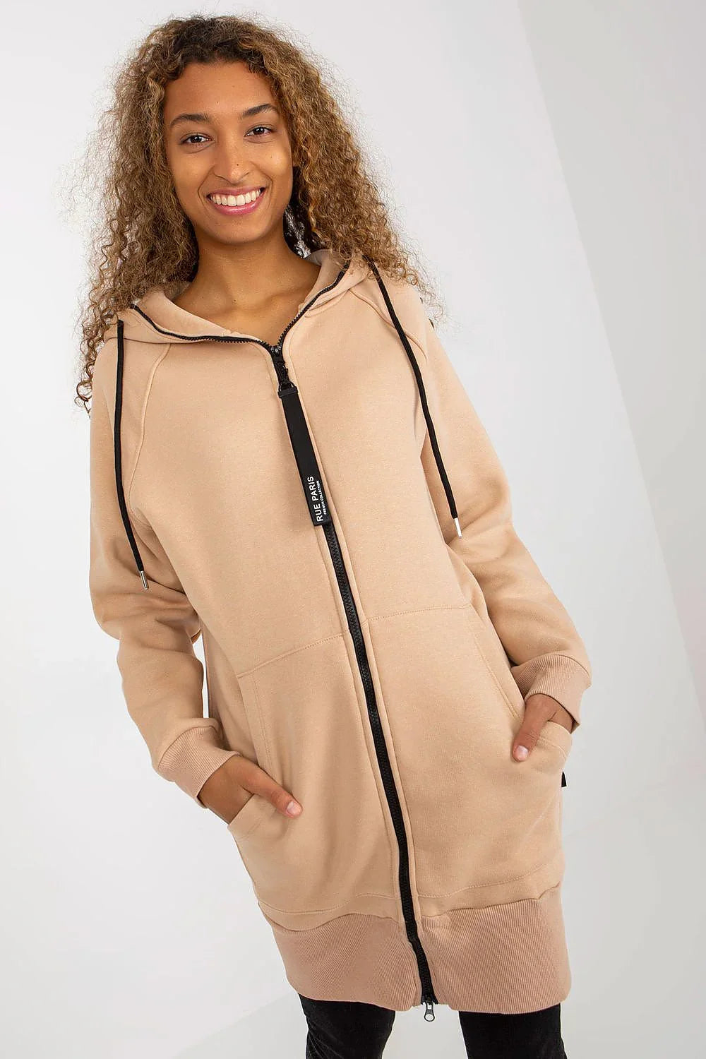 Woman in a long beige zip-up hoodie with a black zip and drawstrings fashion image