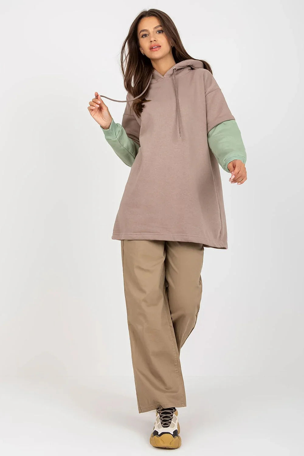Woman in an oversized taupe hoodie with sage green sleeves and wide khaki trousers fashion image