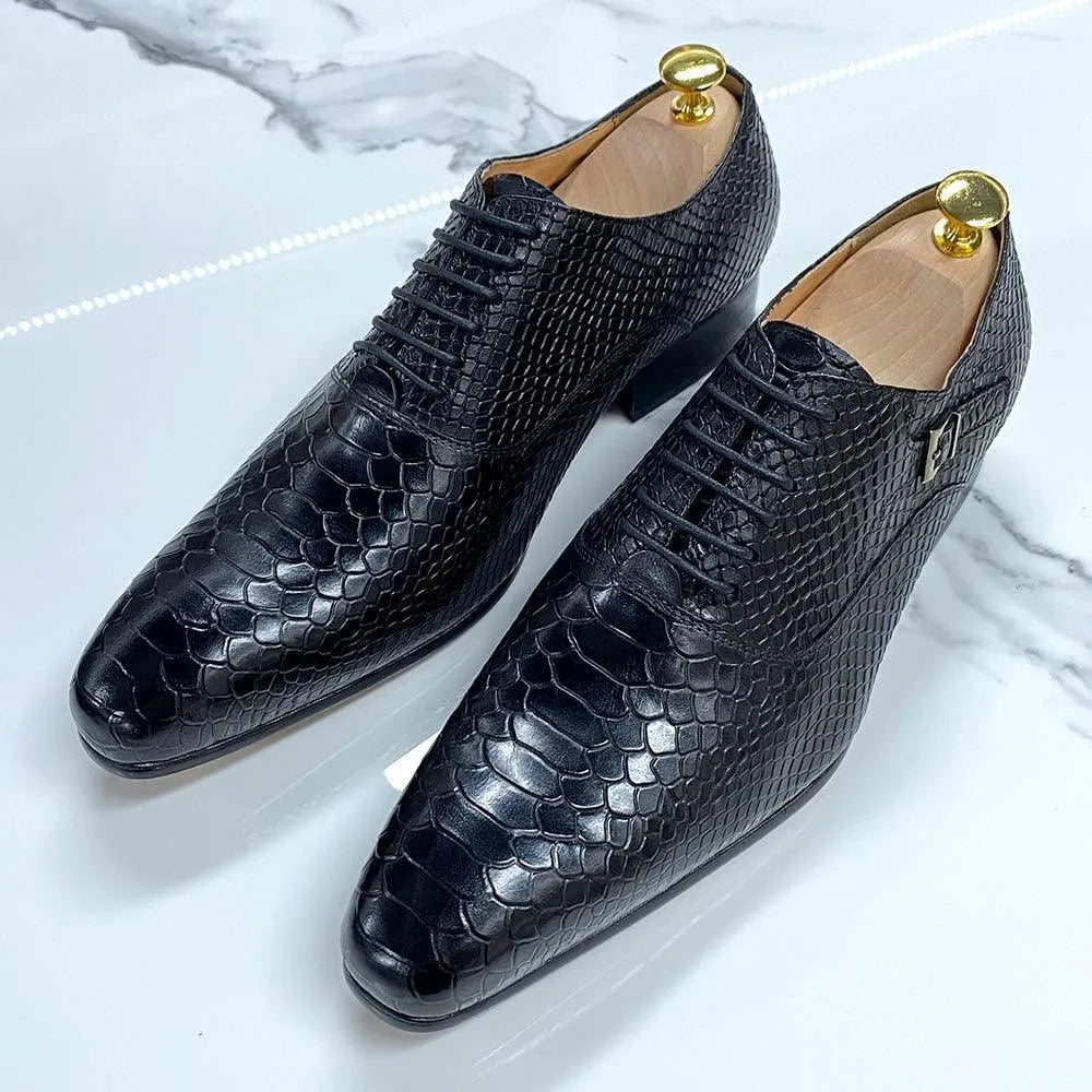 Black snakeskin pattern men's dress shoes on marble surface