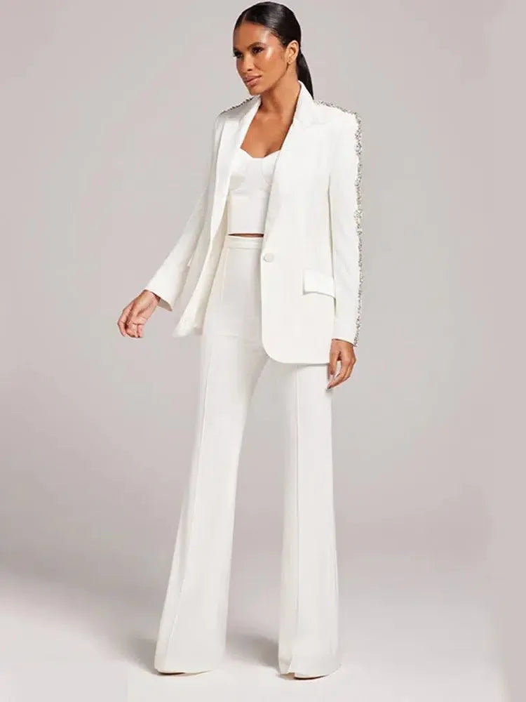 Model in a white blazer with beaded sleeve detail and flared white trousers fashion image