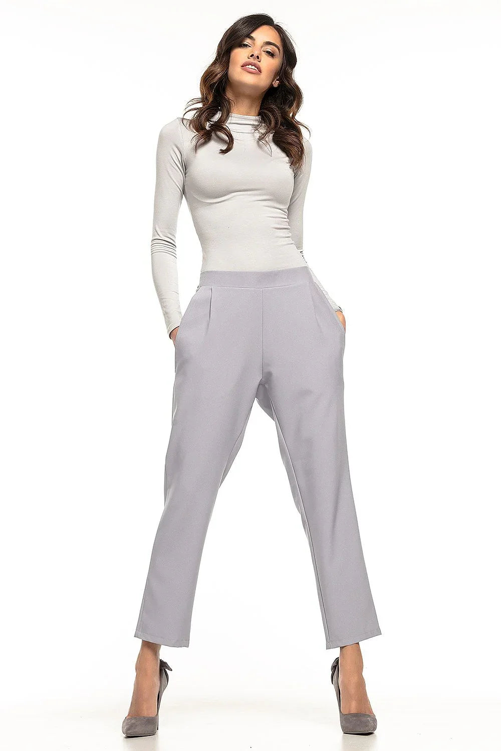 Woman in light grey cropped tapered trousers with a grey top and heels fashion image