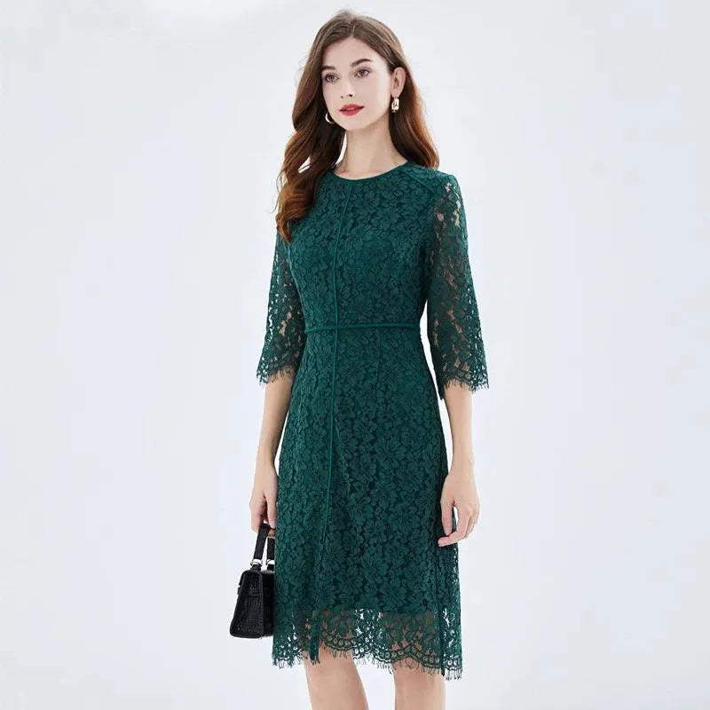 Woman in a dark green lace knee-length dress with three-quarter sleeves, holding a black handbag fashion image