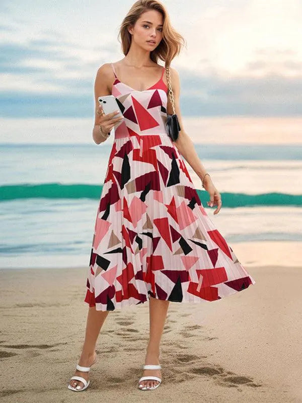 Woman on a beach in a red, pink and black geometric print pleated midi dress fashion image